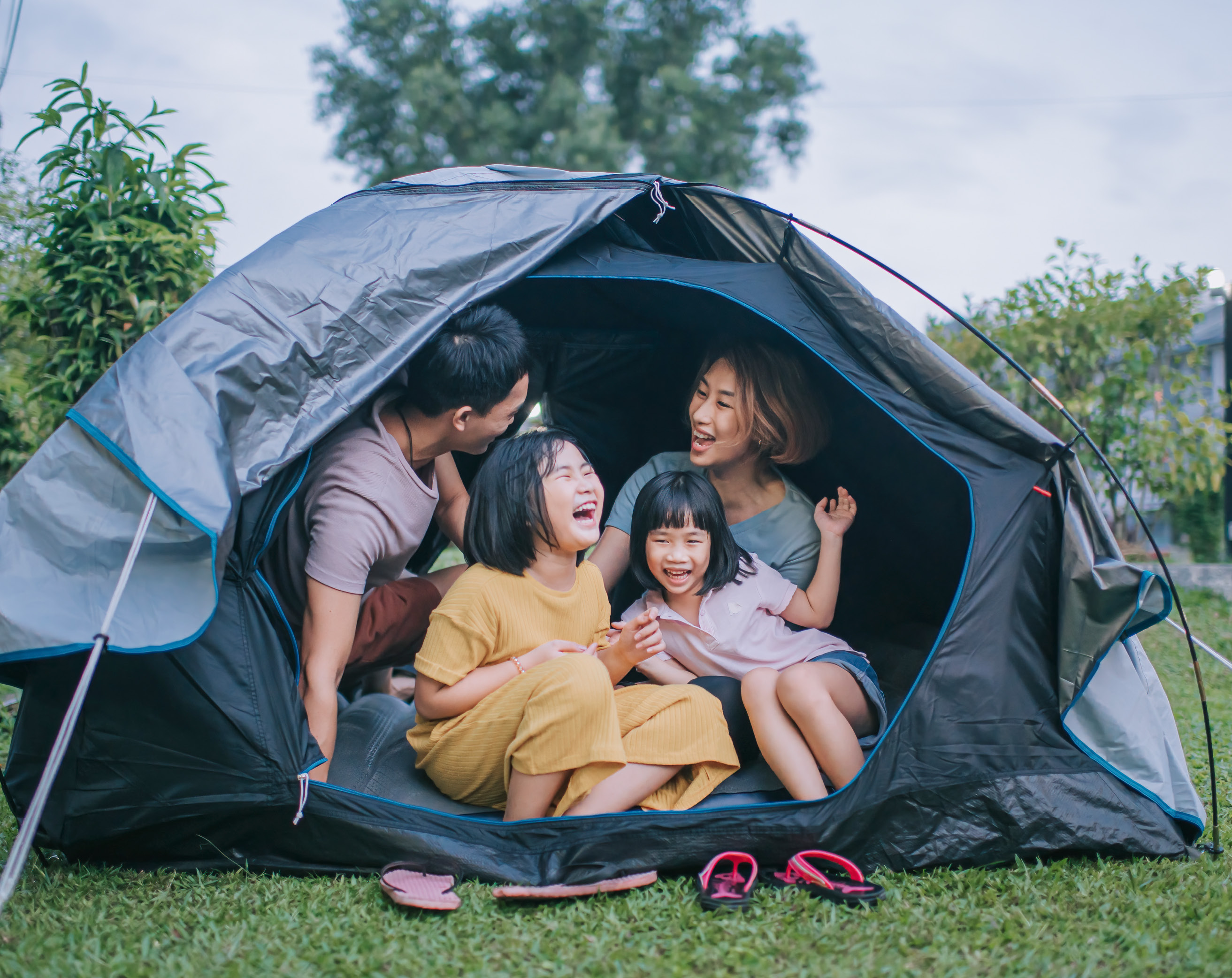 An Asian family laughs while sitting in a tent.
